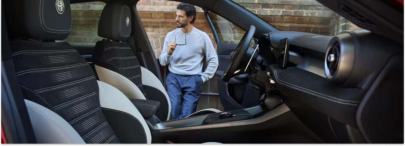 Interior view of a 2026 Alfa Romeo Tonale showing two-tone black and grey front seats and the dashboard.