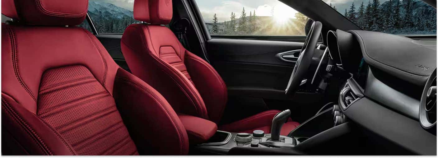 Red leather front bucket seats and dashboard inside a 2026 Alfa Romeo Giulia.