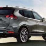 Gray Nissan Rogue parked in front of a cityscape at sunset