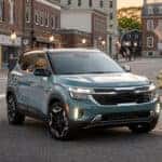 Light blue kia seltos on a road in a small downtown city