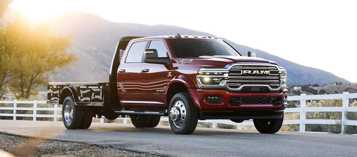 Powerful RAM 3500 Chassis Cab in red, featuring a rugged flatbed design, parked on a scenic country road. Available at Bernard Northtown.
