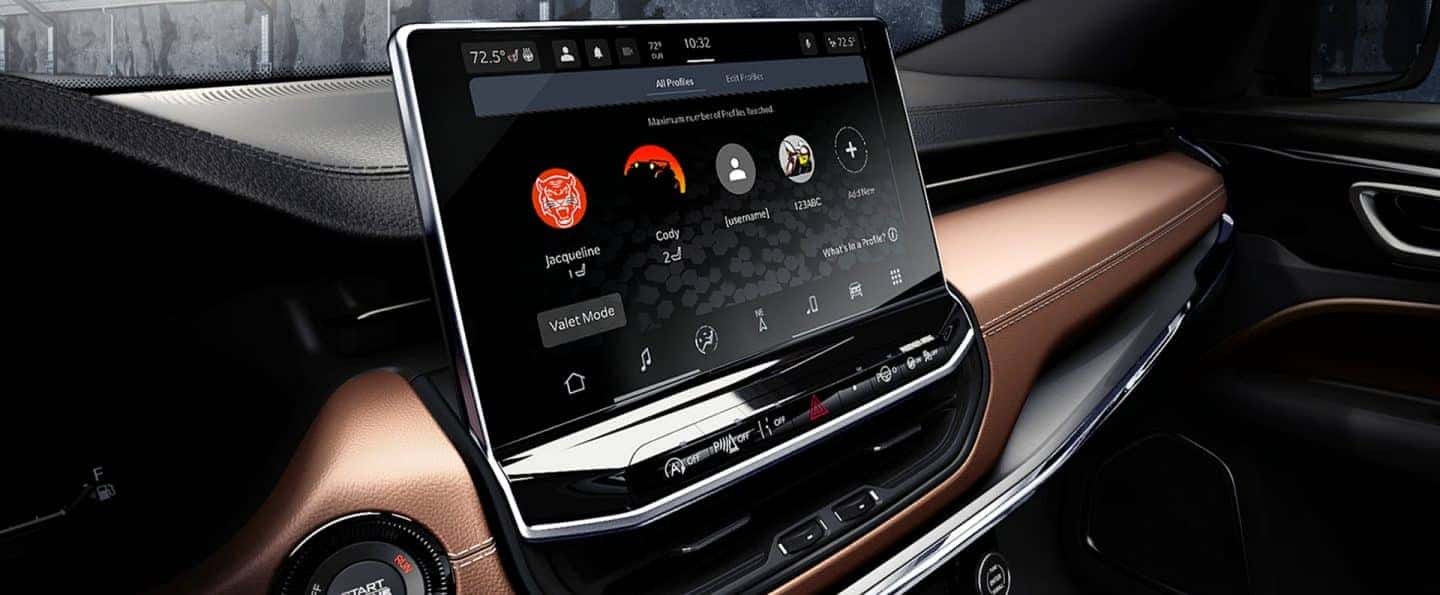 Close-up of the 2025 Jeep Compass interior featuring a Uconnect® infotainment touchscreen with personalized profiles and leather dashboard, available at Bernard's Northtown Jeep.