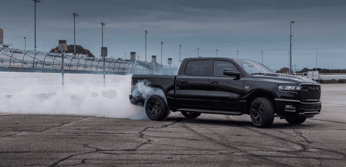 2026 Black RAM 1500 Express truck doing a burnout on a racetrack with smoke trailing from the rear tires.