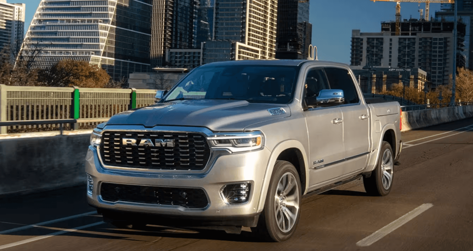 Silver RAM 1500 driving on a city street with modern skyscrapers in the background.