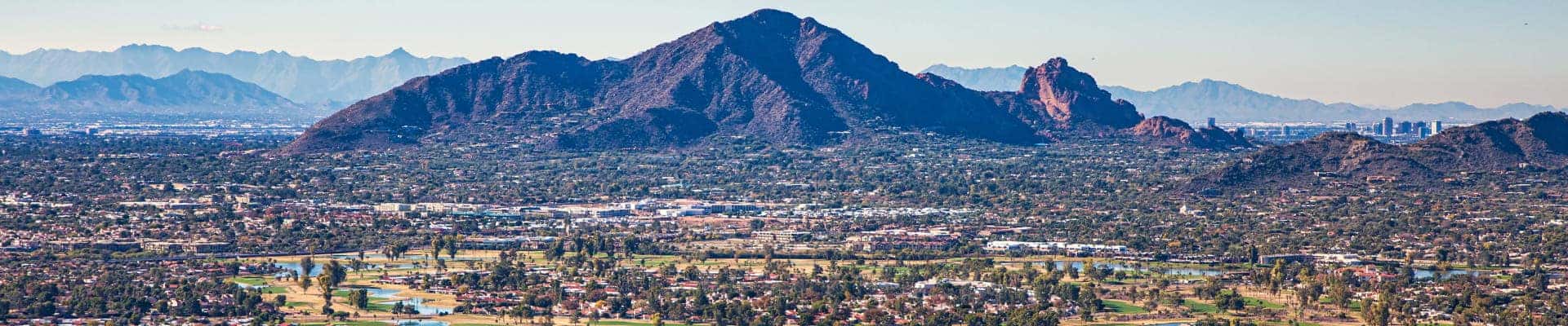 Panoramic view of a suburban community surrounded by rugged desert mountains.