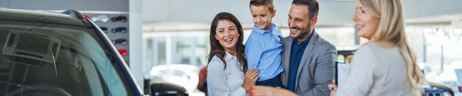 Family viewing a vehicle with a sales representative inside a car dealership