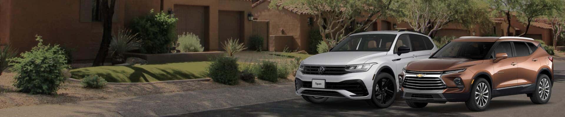 Front three-quarter view of a white 2023 Volkswagen Tiguan and bronze 2023 Chevrolet Blazer on a neighboorhood street.