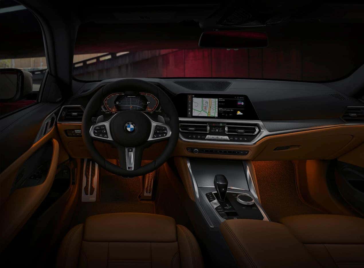 A black sapphire metallic BMW 2 Series Gran Coupe driving past a red and yellow building.