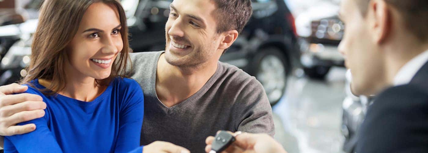 young couple getting keys at dealership