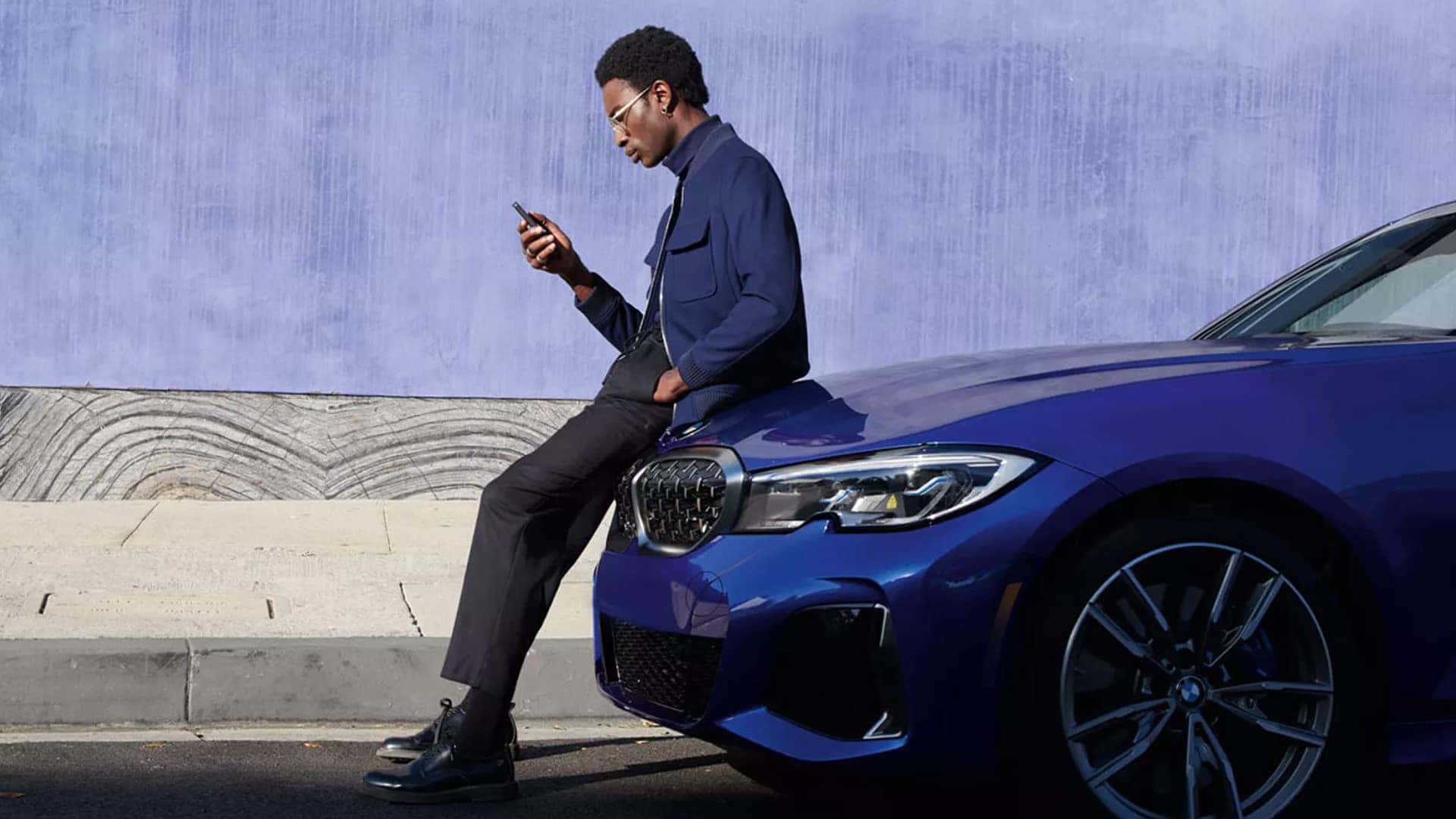 Man Using BMW App Leaning on 2026 BMW iX