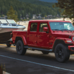 A red 2021 Jeep Gladiator towing a boat.