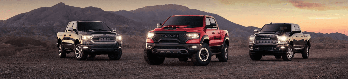 Three different RAM trucks parked on a dirt road.