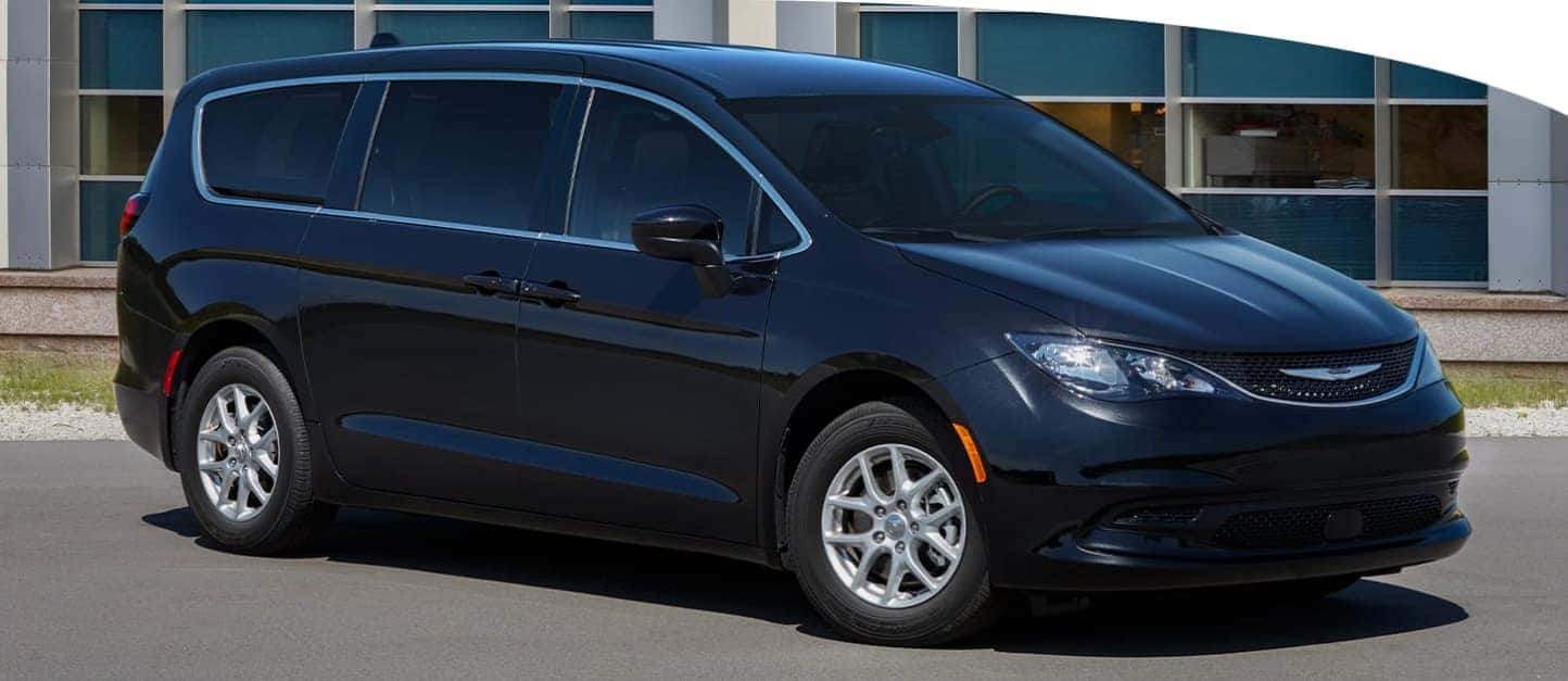 A black Chrysler Voyager parked in front of a building.