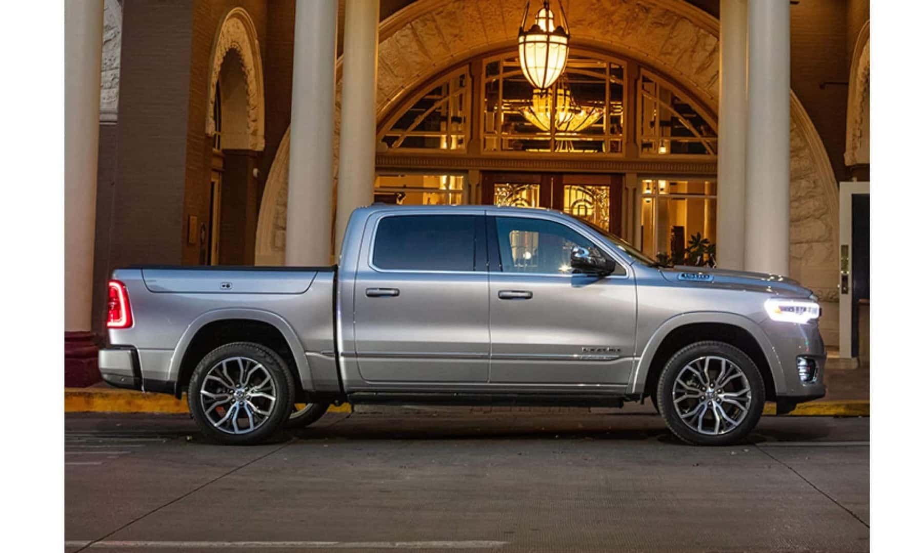 A silver RAM 1500 pickup truck, parked in front of a hotel