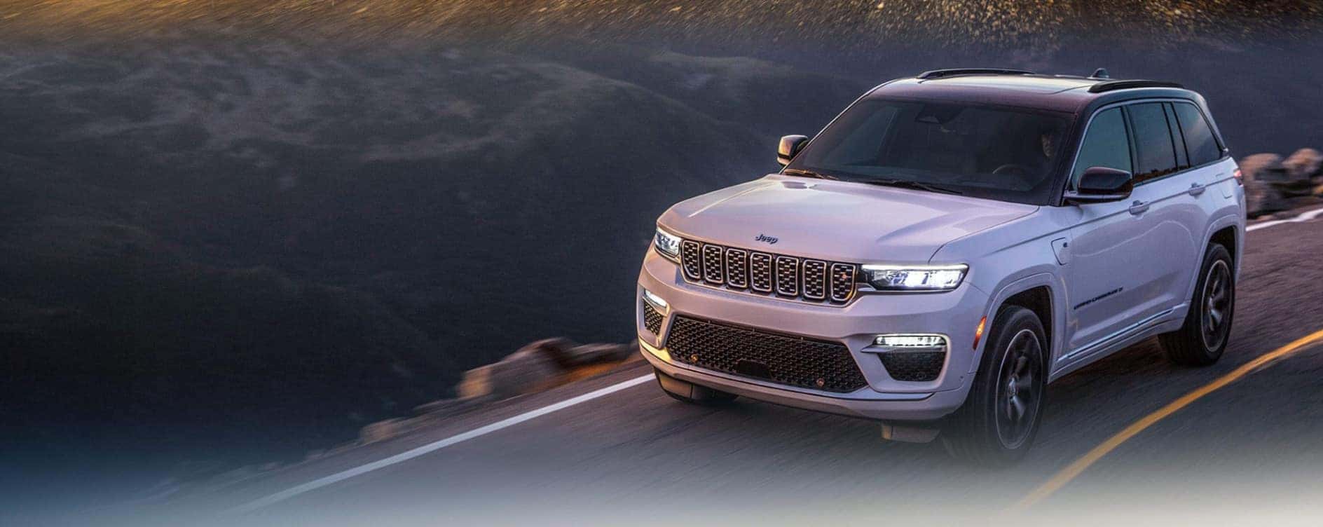 A pink Jeep Grand Cherokee driving in a mountainous region.