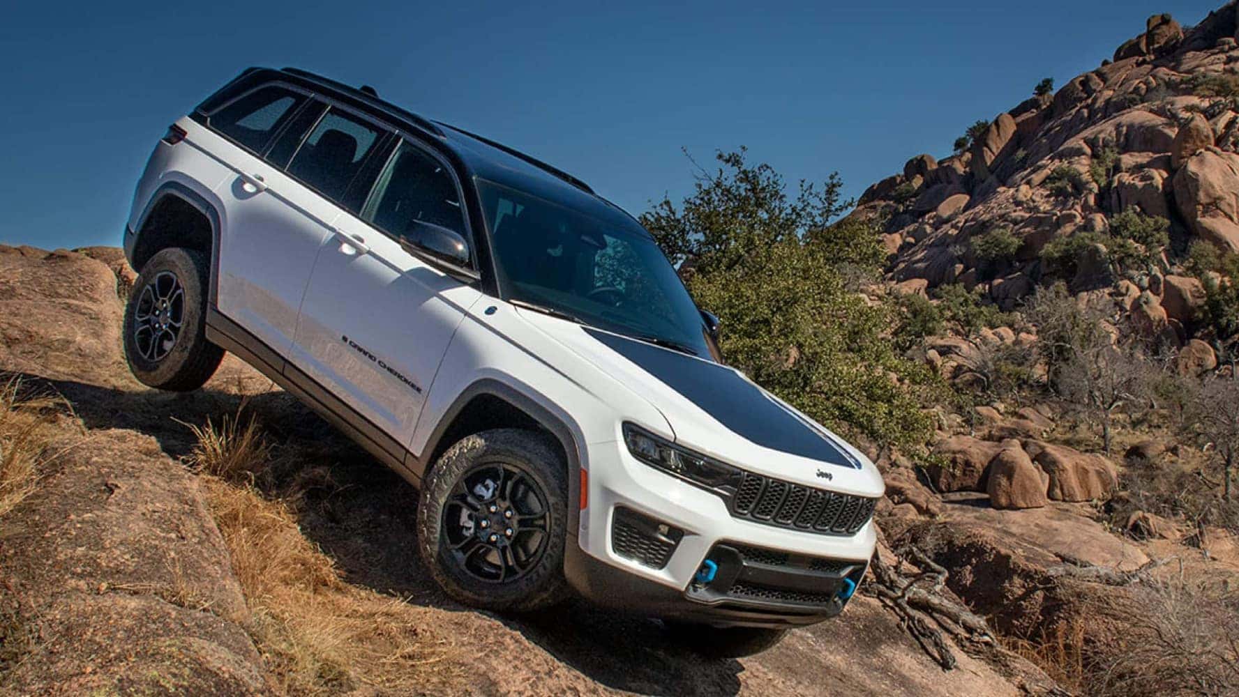 A white Jeep Grand Cherokee driving down a rocky incline.