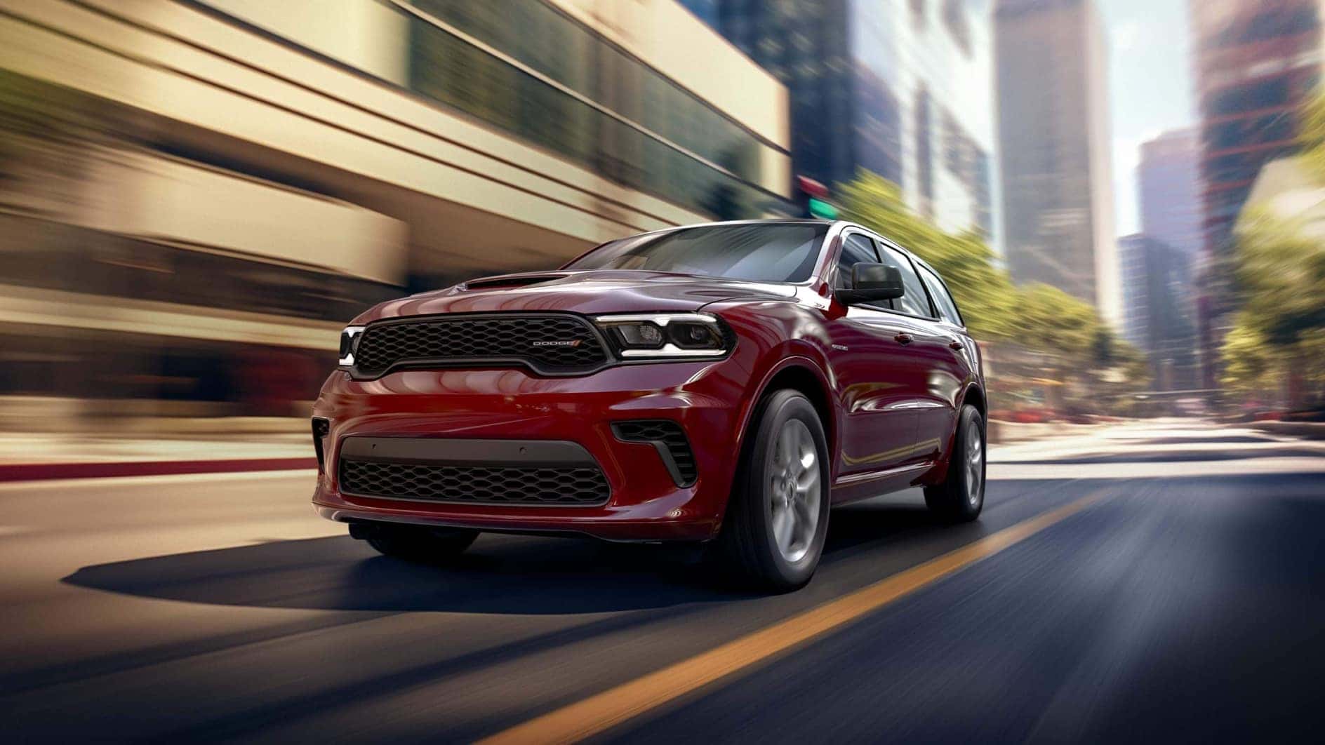A red Dodge Durango driving quickly through a city.