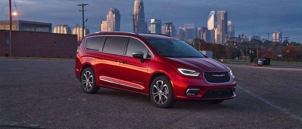 A red Chrysler Pacifica parked outside a city. A red Chrysler Pacifica parked outside a city.