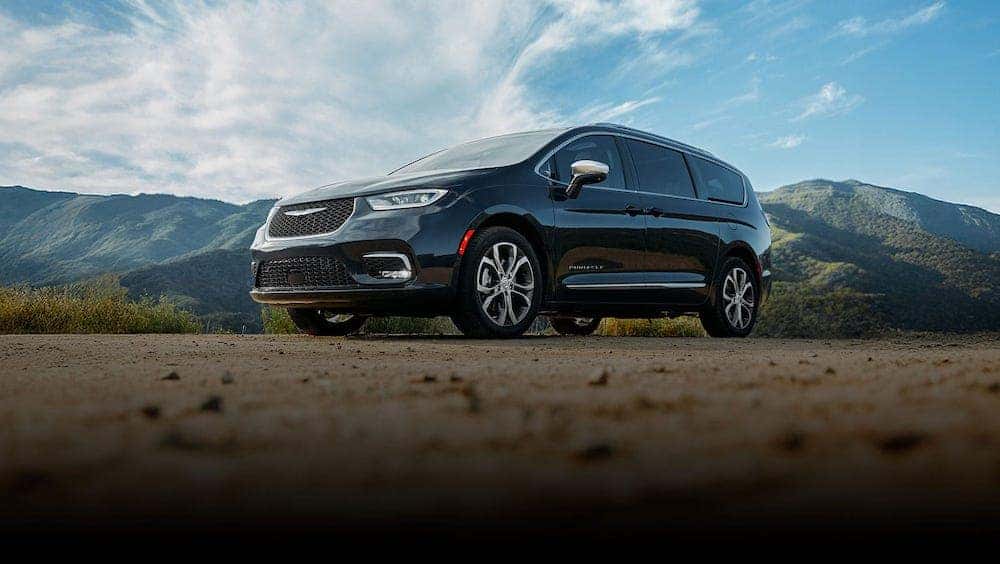 A black Chrysler Pacifica off-road with a mountain range backdrop A black Chrysler Pacifica off-road with a mountain range backdrop