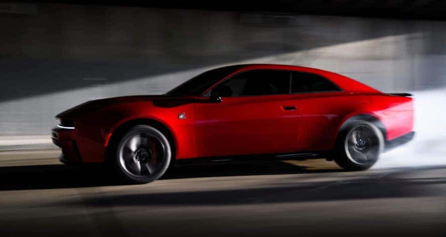 A red Dodge Charger quickly driving into a tunnel in profile.