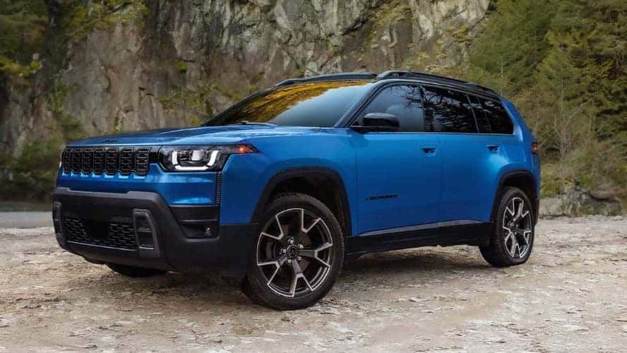 A blue Jeep Cherokee parked at the bottom of a cliff.