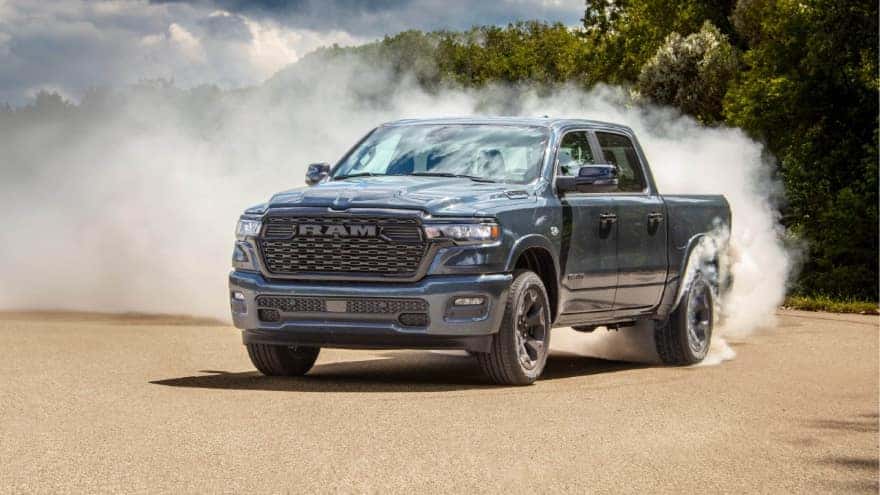 A light blue RAM 1500 kicking up dust as it drives off-road.