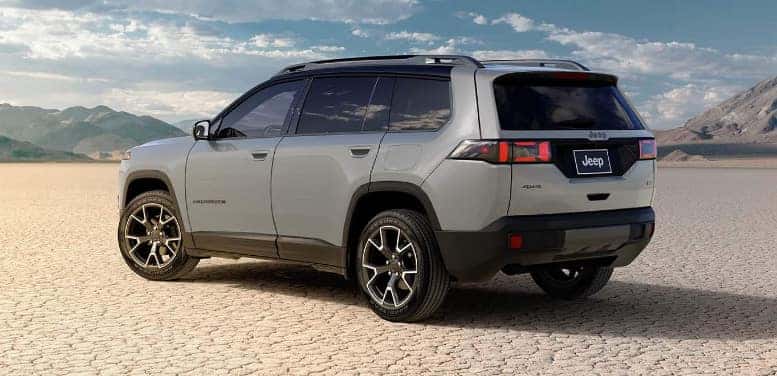 A light gray Jeep Cherokee parked in the middle of a dry lakebed or desert.