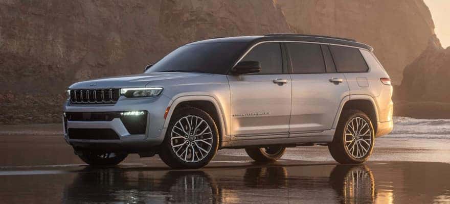 A silver Jeep Grand Cherokee parked on a beach in profile.