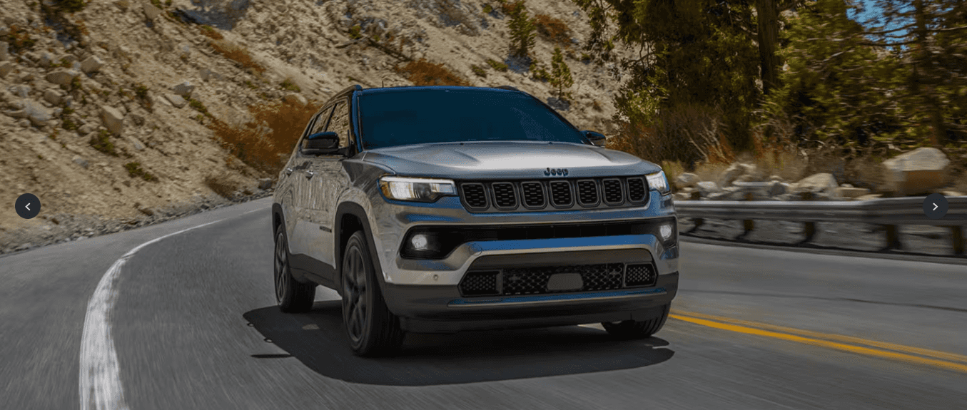 A front view of a gray Jeep Compass driving down the road.