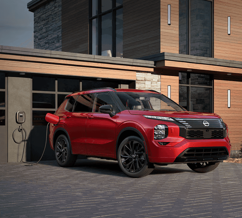Red Nissan eelctric SUV parked and plugged in for charging