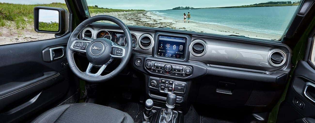 The black interior is shown in a 2021 Jeep Wrangler with a beach in the windshield.