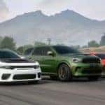 A white 2020 Dodge Charger, green Durango, and red Challenger are driving side by side past a mountain.