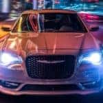 A white 2021 Chrysler 300 is shown from the front driving through the city after leaving a Lexington Chrysler dealership.