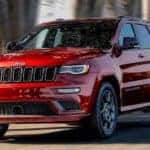 A red 2020 Jeep Grand Cherokee is shown driving through a city.