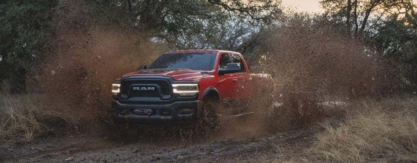A red 2022 Ram 2500 Power Wagon is shown from the front at an angle while driving through mud.