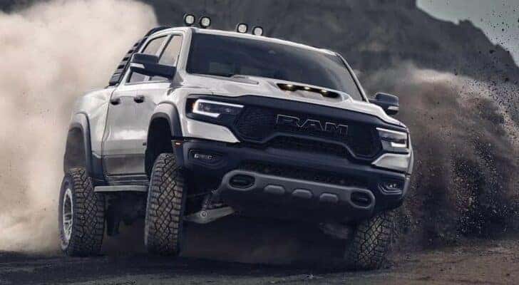 A white 2023 Ram 1500 TRX is shown off-roading after visiting a used Ram dealership.