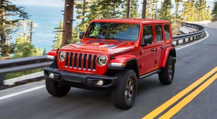 A red 2021 Jeep Wrangler Rubicon is shown driving near a lake.