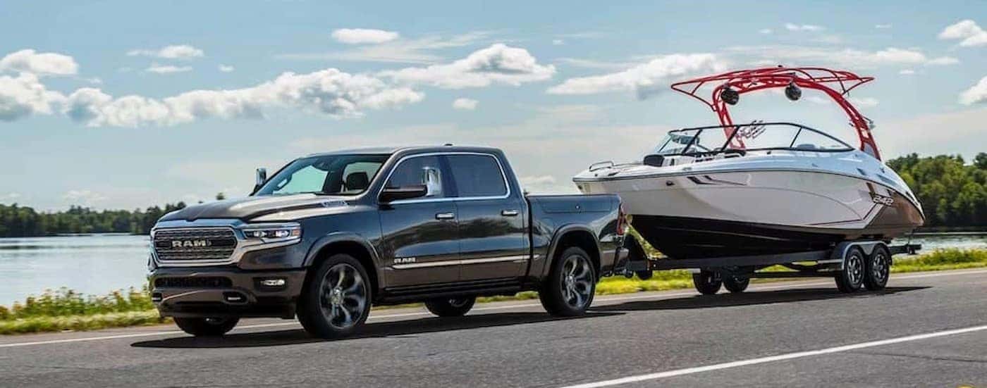 A black 2024 Ram 1500 is shown towing a boat.