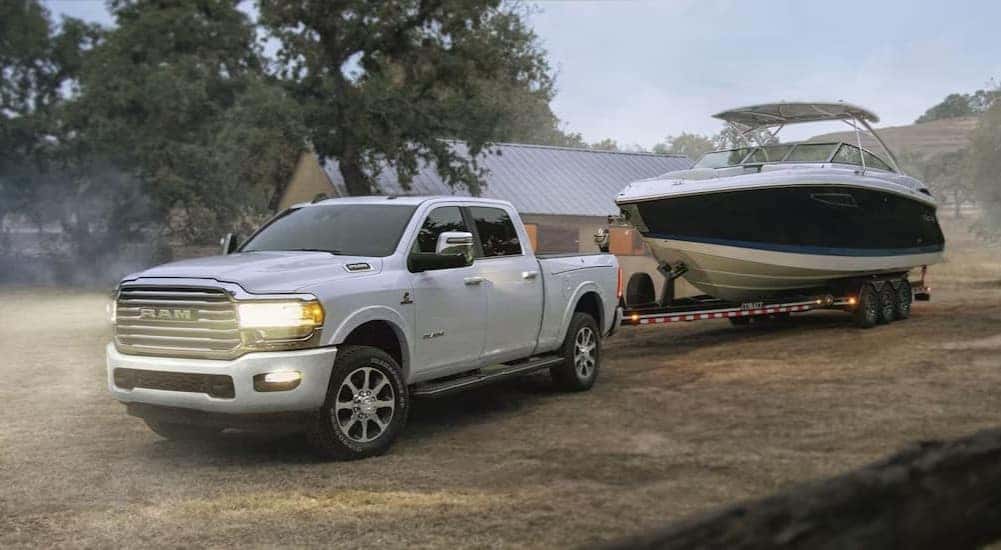 A white 2024 Ram 2500 is shown towing a boat.