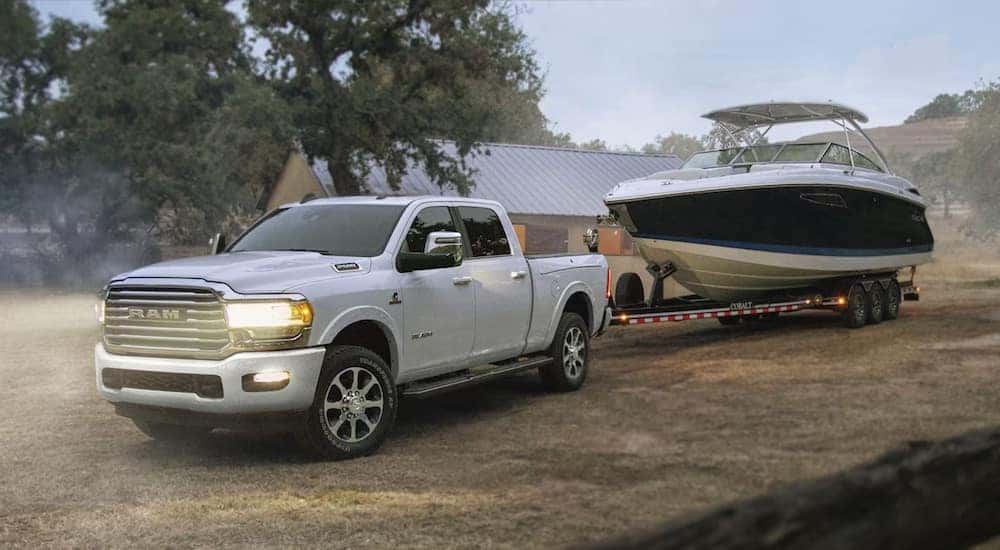 A white 2024 Ram 2500 HD Limited Longhorn is shown from the front at an angle while towing a boat.