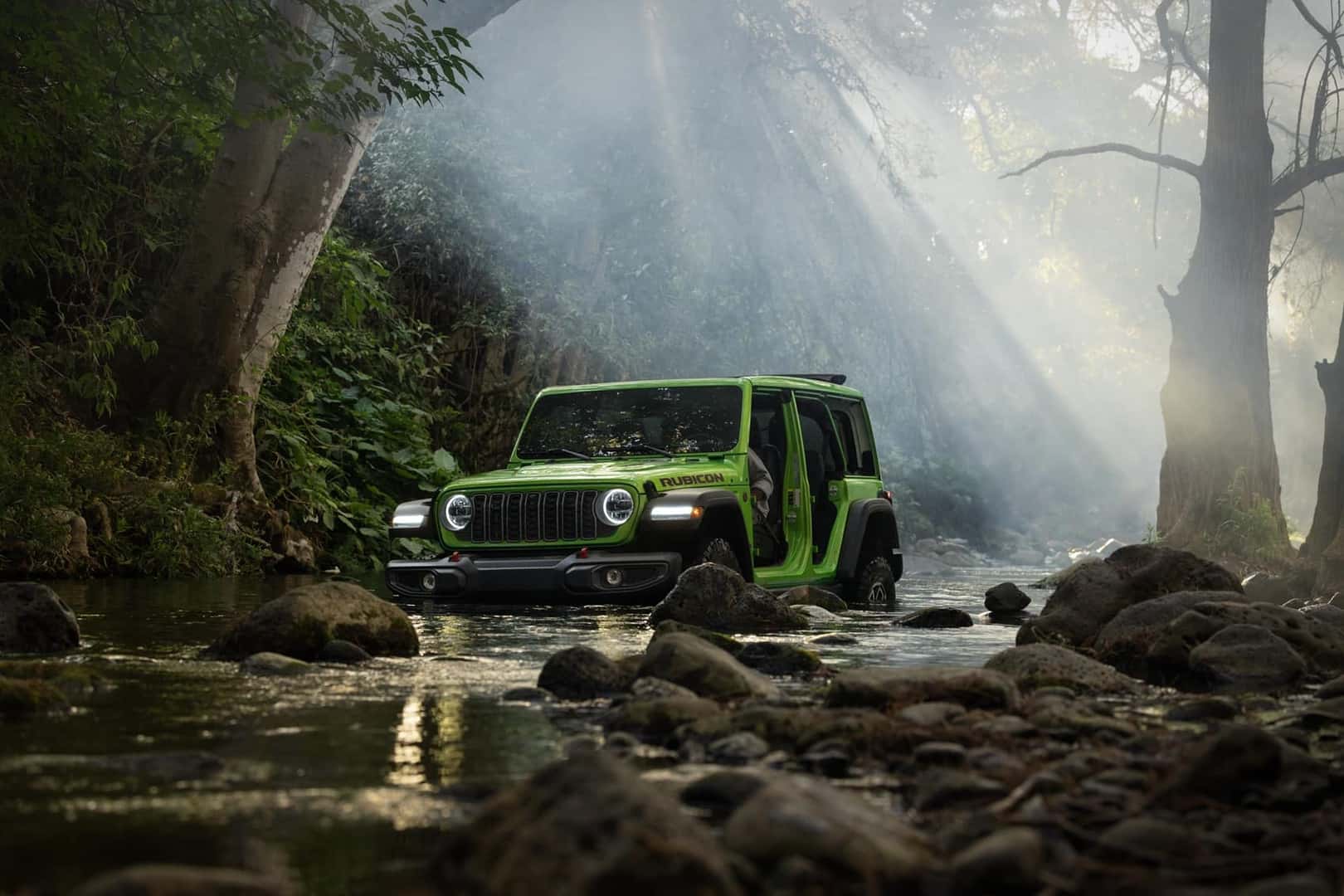 2026 Jeep Wrangler Rubicon in a forest river with no doors and open sunroof