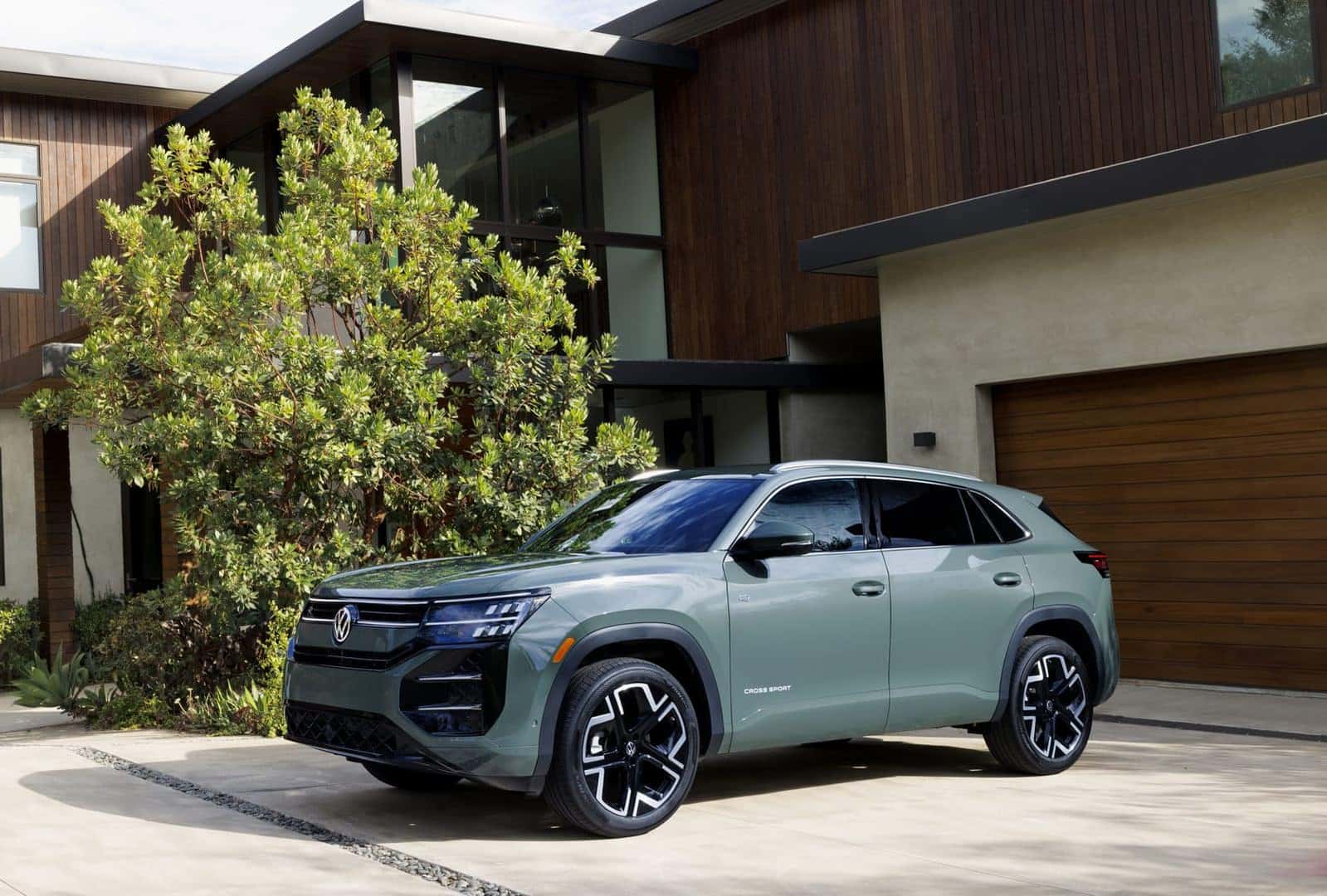 Front three-quarter view of the 2027 Volkswagen Atlas Cross Sport in Dark Sage Metallic at a Denver Volkswagen dealership