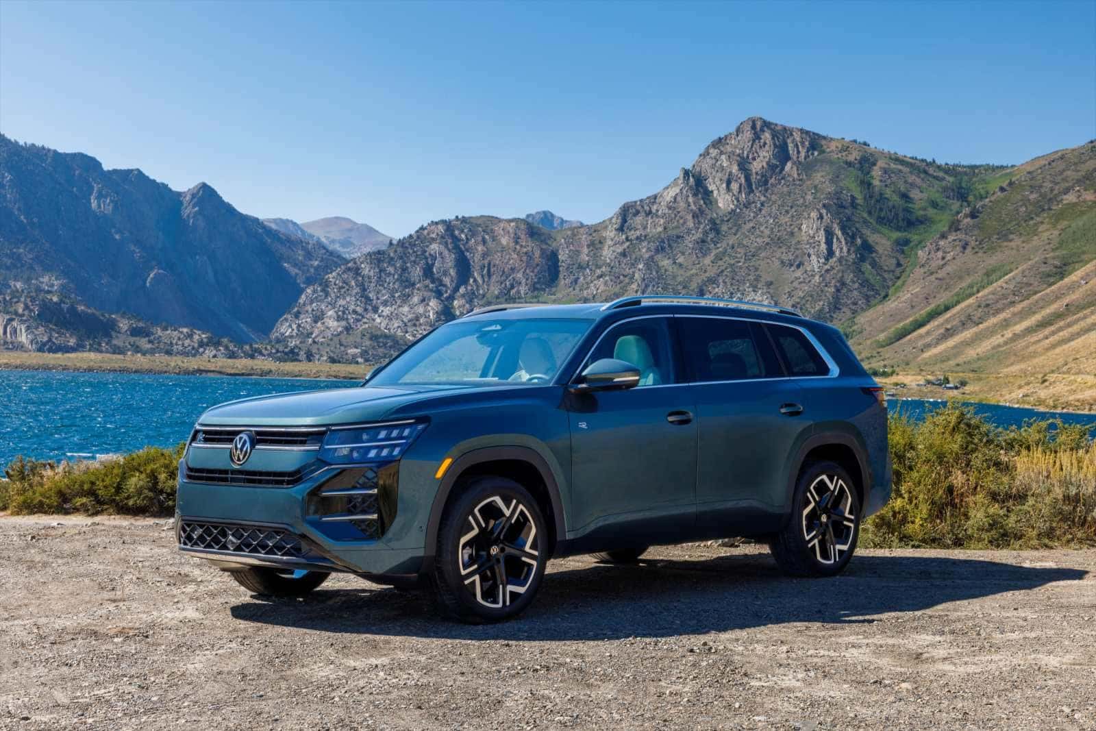 All-new 2027 Volkswagen Atlas in Sacramento Green Metallic beside a mountain lake, available at Emich Volkswagen in Denver