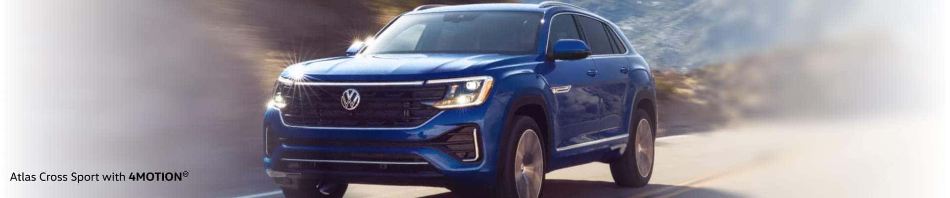 A blue Volkswagen Atlas Cross Sport SUV with 4MOTION drives on a scenic mountain road.