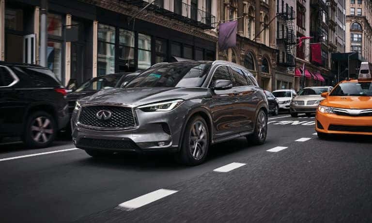 2023 INFINITI QX50 driving on a bridge in a large city