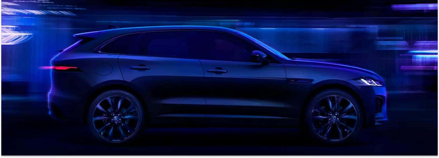 Side profile of a dark blue 2026 Jaguar F-PACE with neon motion blur.