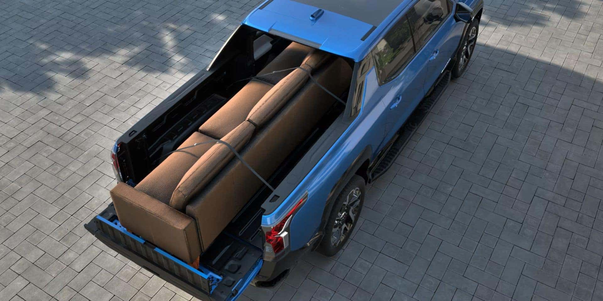 Top-down view of the 2025 Chevrolet Silverado EV's truck bed carrying a large couch, secured with straps.