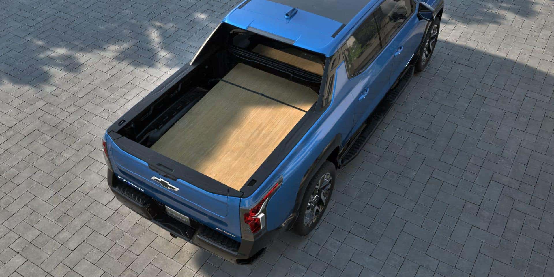 Top-down view of the 2025 Chevrolet Silverado EV's truck bed with a flat wooden surface, showcasing its versatile cargo space.