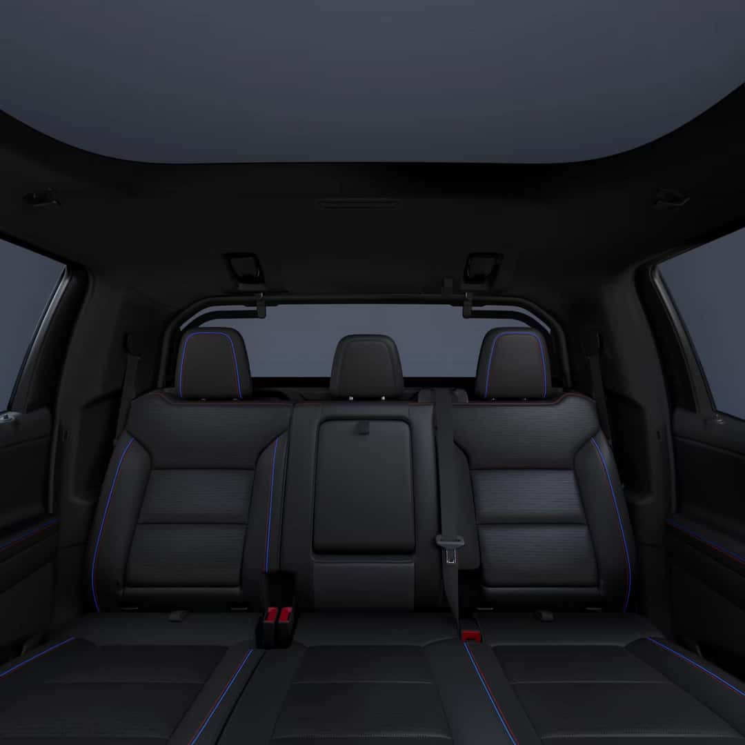 back passenger seat view of chevy silverado ev with black leather interior and blue and red stitching.