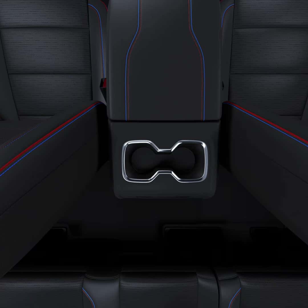 top view of the center console and cupholders in the 2025 silverado ev with black leather interior and red and blue stitching.